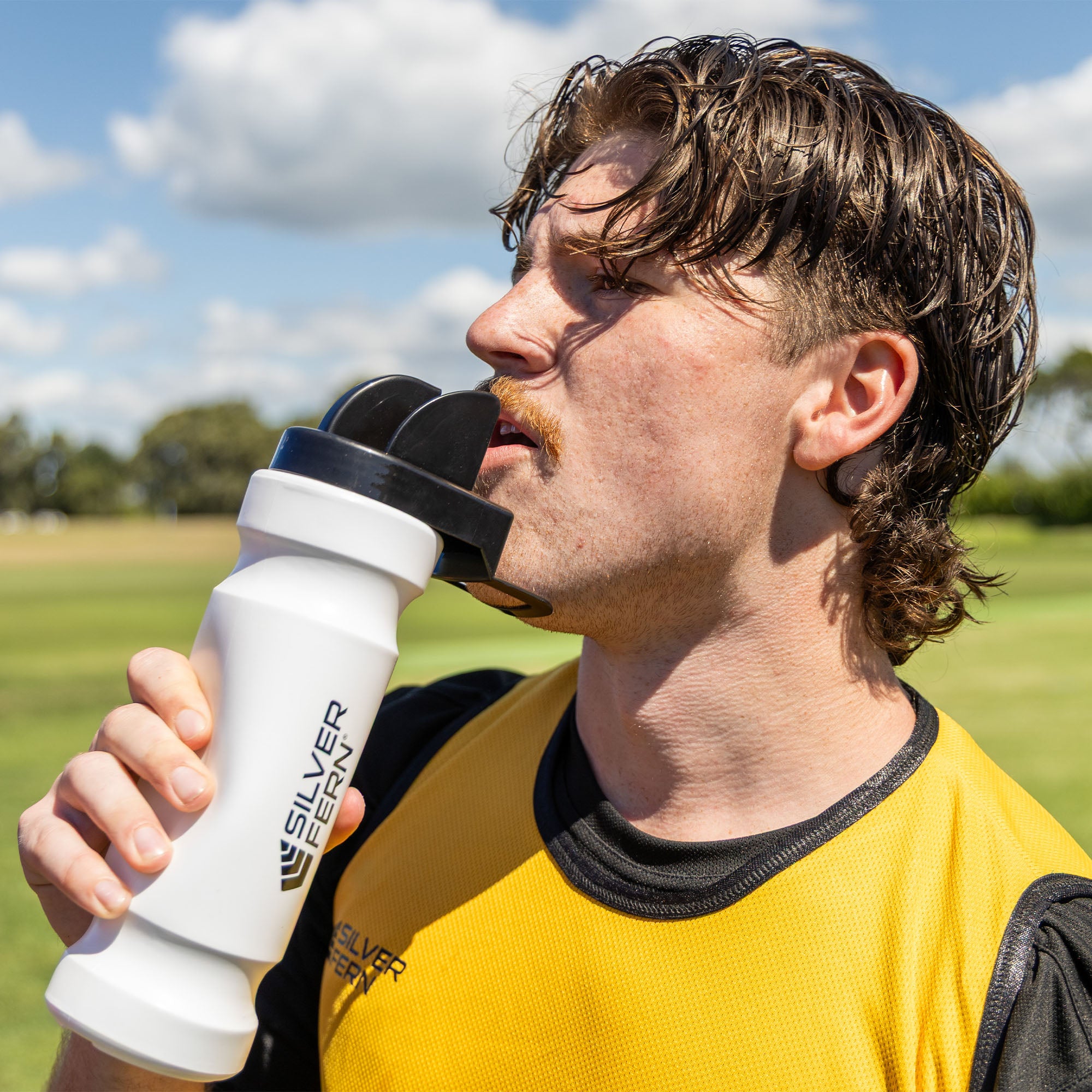 Hygiene drink bottle, rugby player squeezing the bottle and drinking water out of the hygiene chin rest cap, lifestyle.